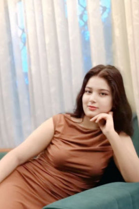Woman in a brown dress sitting on a green couch with a light blue wall in the background