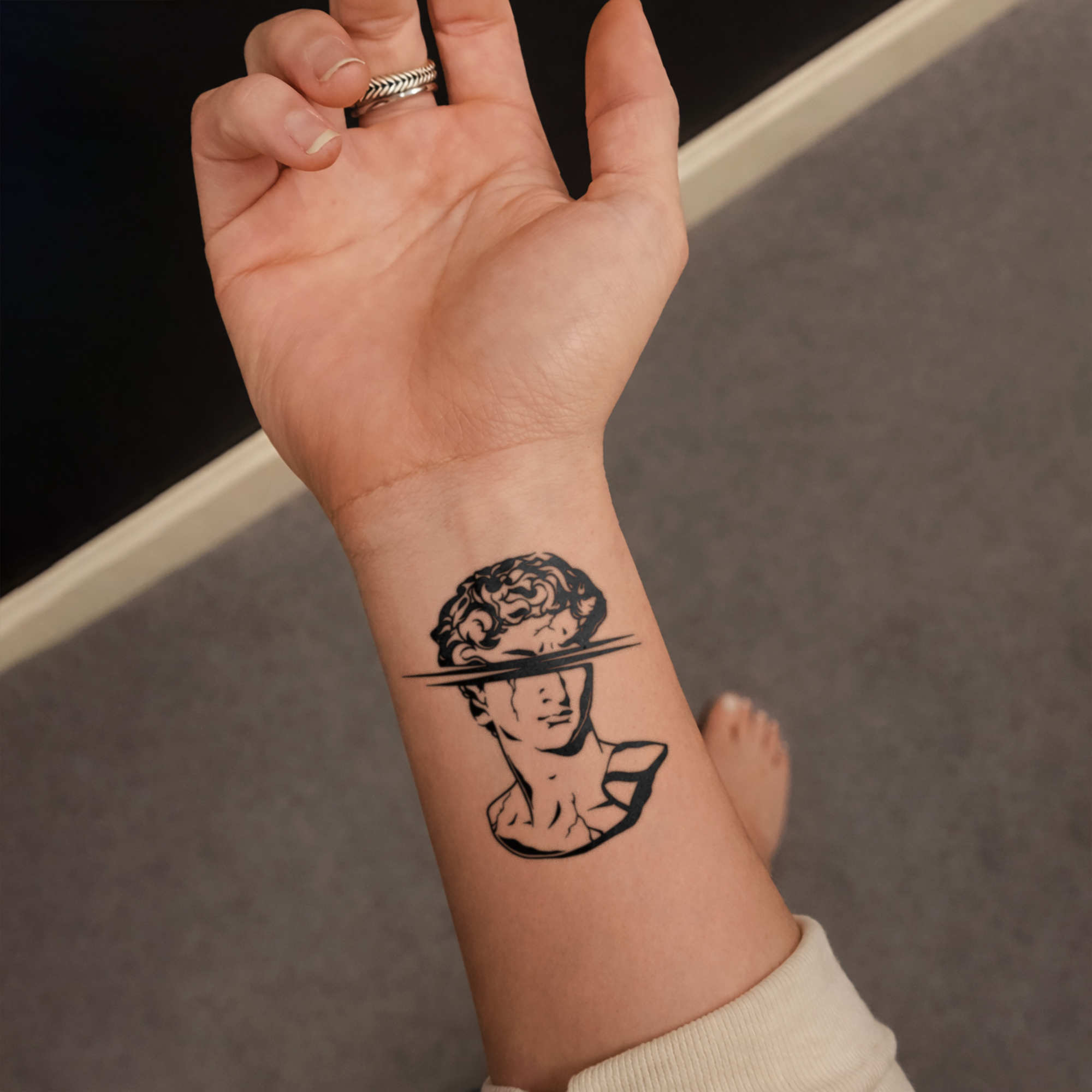 Hand with a temporary tattoo of a stylized portrait on a neutral background