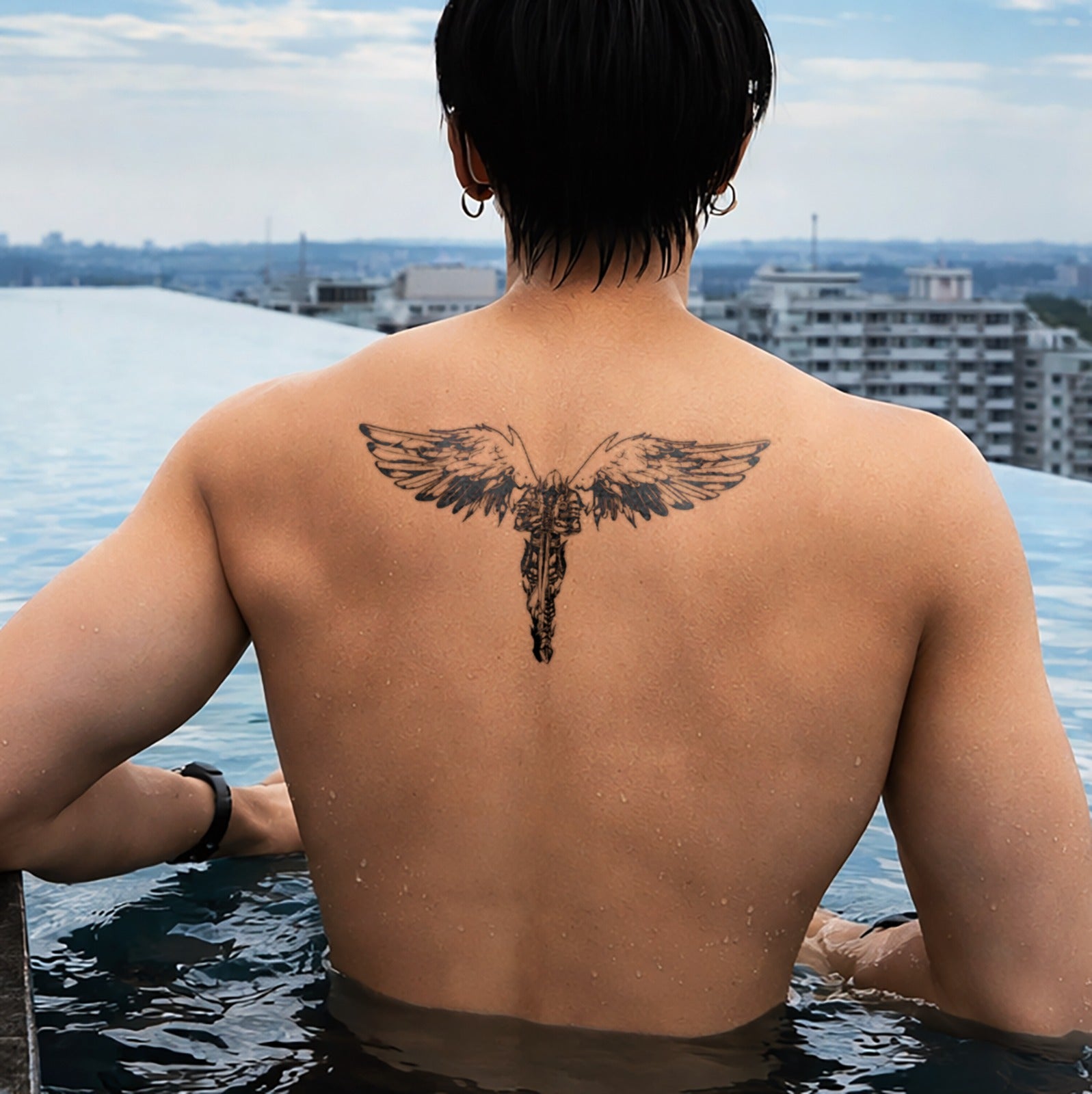 Person with a tattoo on their back overlooking a cityscape from a high vantage point.
