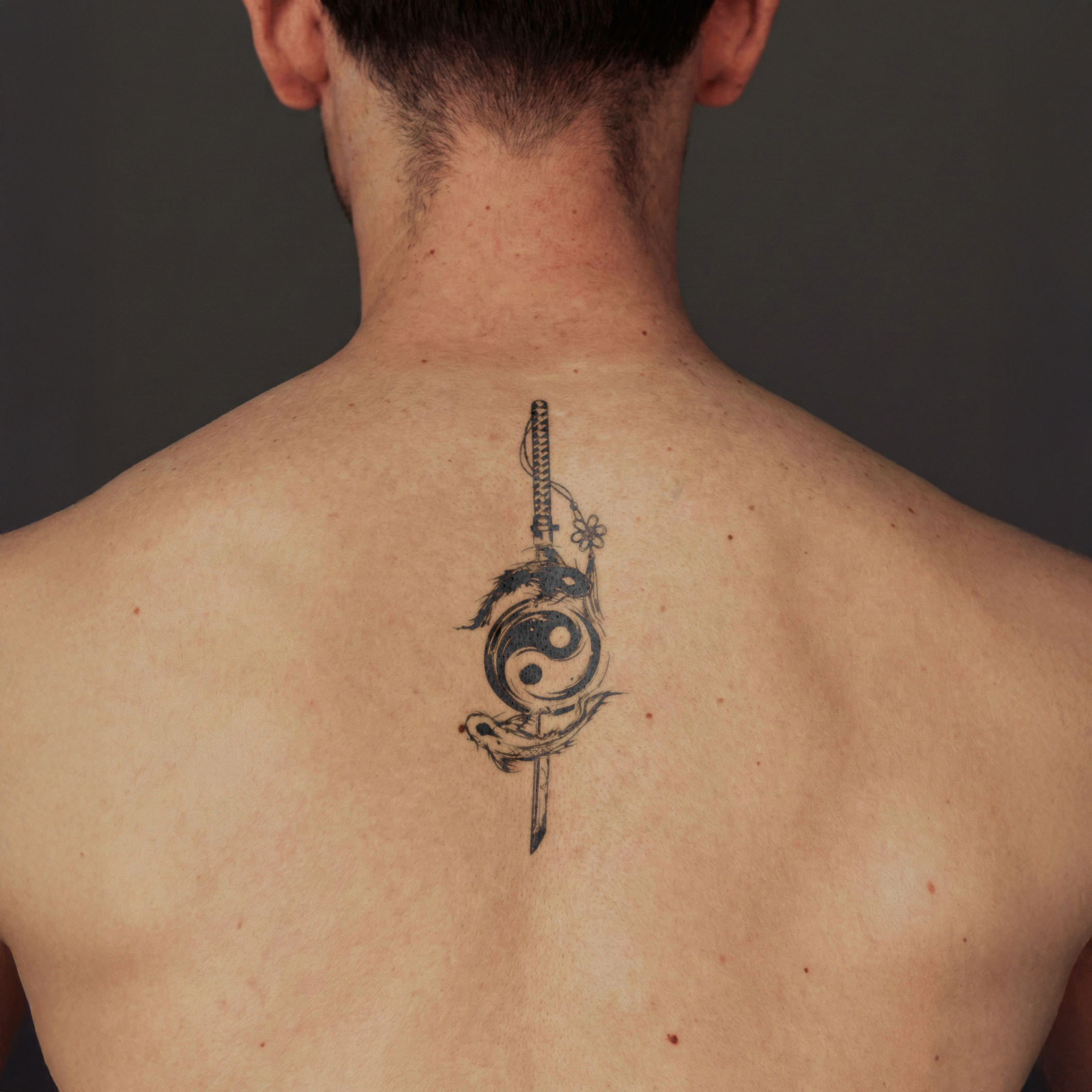 Person with a tattoo on their back against a dark background