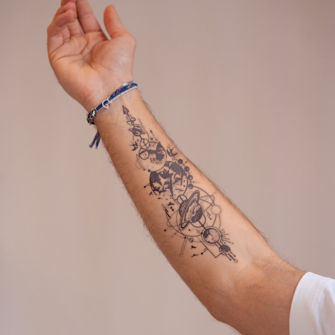 Arm with a tattoo of celestial designs on a plain background
