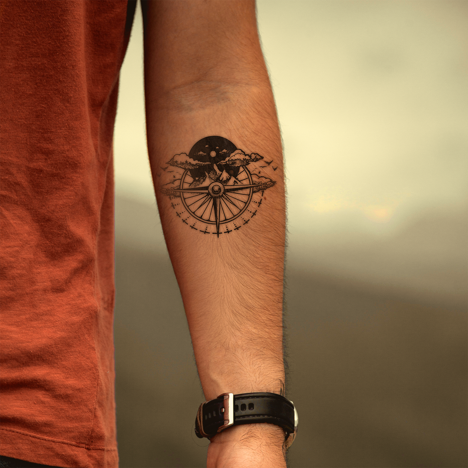 Tattoo of a compass on a person's arm with a blurred background