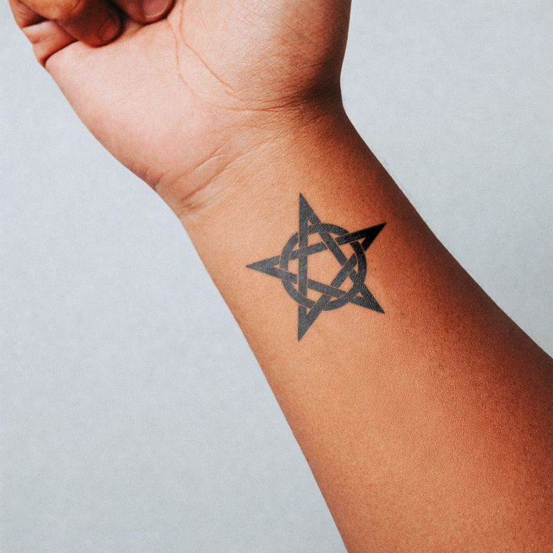 Star tattoo on a person's wrist against a light gray background