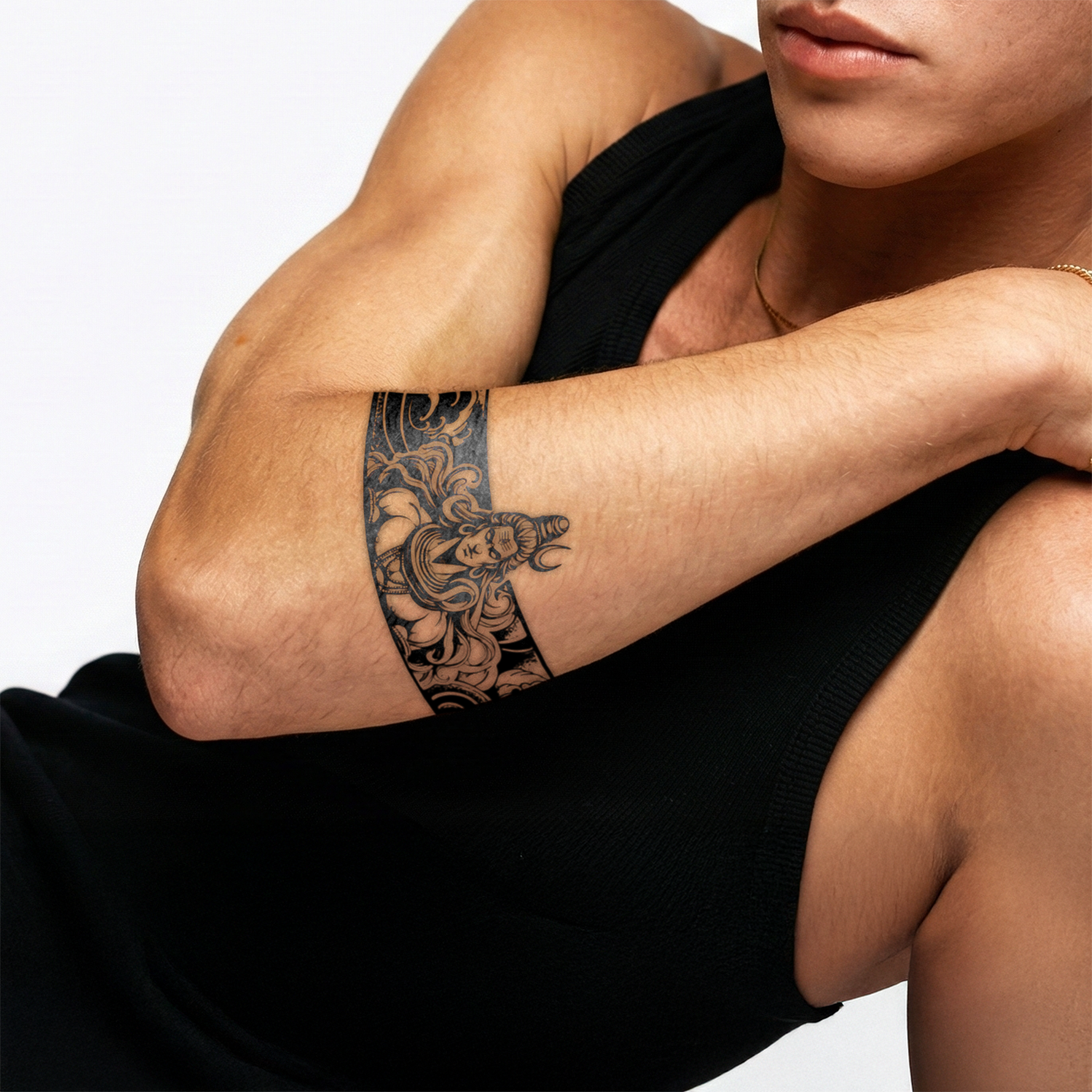 Person wearing a black tank top with a tattoo on their arm against a white background
