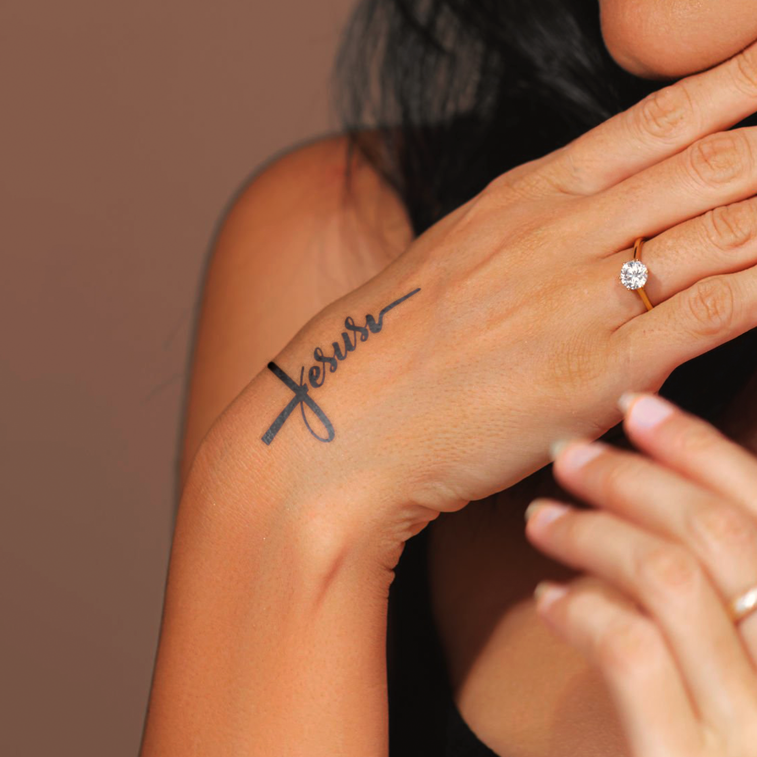 Hand with 'forever' tattoo on wrist against a neutral background