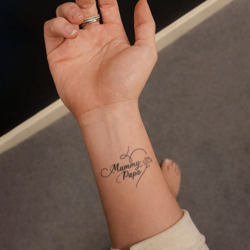 Hand with a tattoo of 'Mummy Papa' on a neutral background