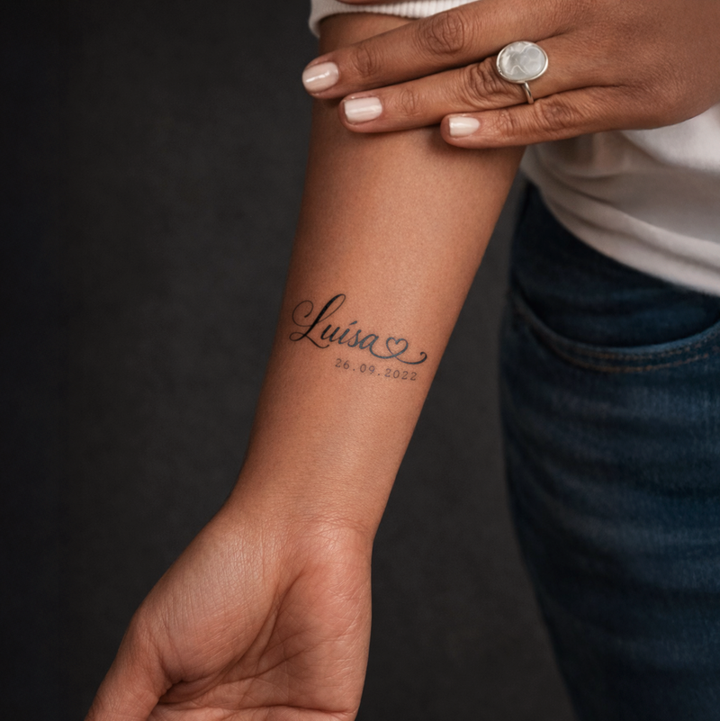 Person with a tattoo on their wrist and a ring on their finger against a dark background