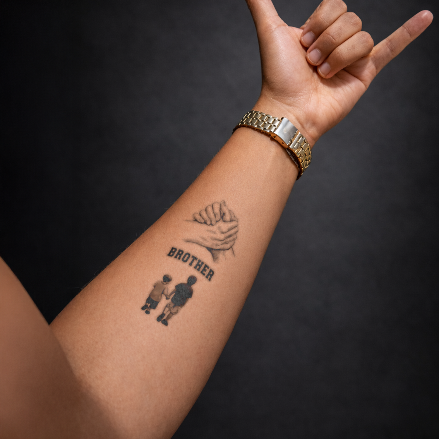 Hand with tattoo of 'Brother' and two figures, wearing a gold watch on a dark background
