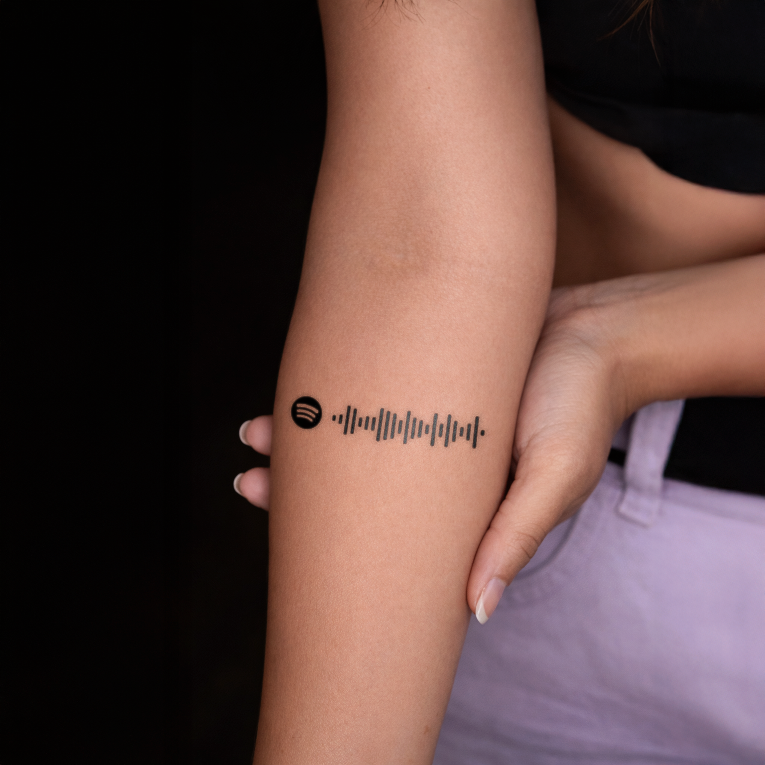 Person with a tattoo on their arm displaying '25.11.2021' against a black background