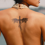 Person with a dragon tattoo on their back, wearing a decorative headpiece.
