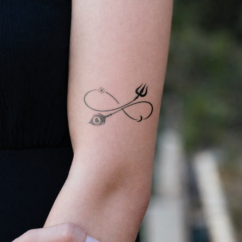 Black tattoo of a trident and infinity symbol on a person's arm with a blurred natural background