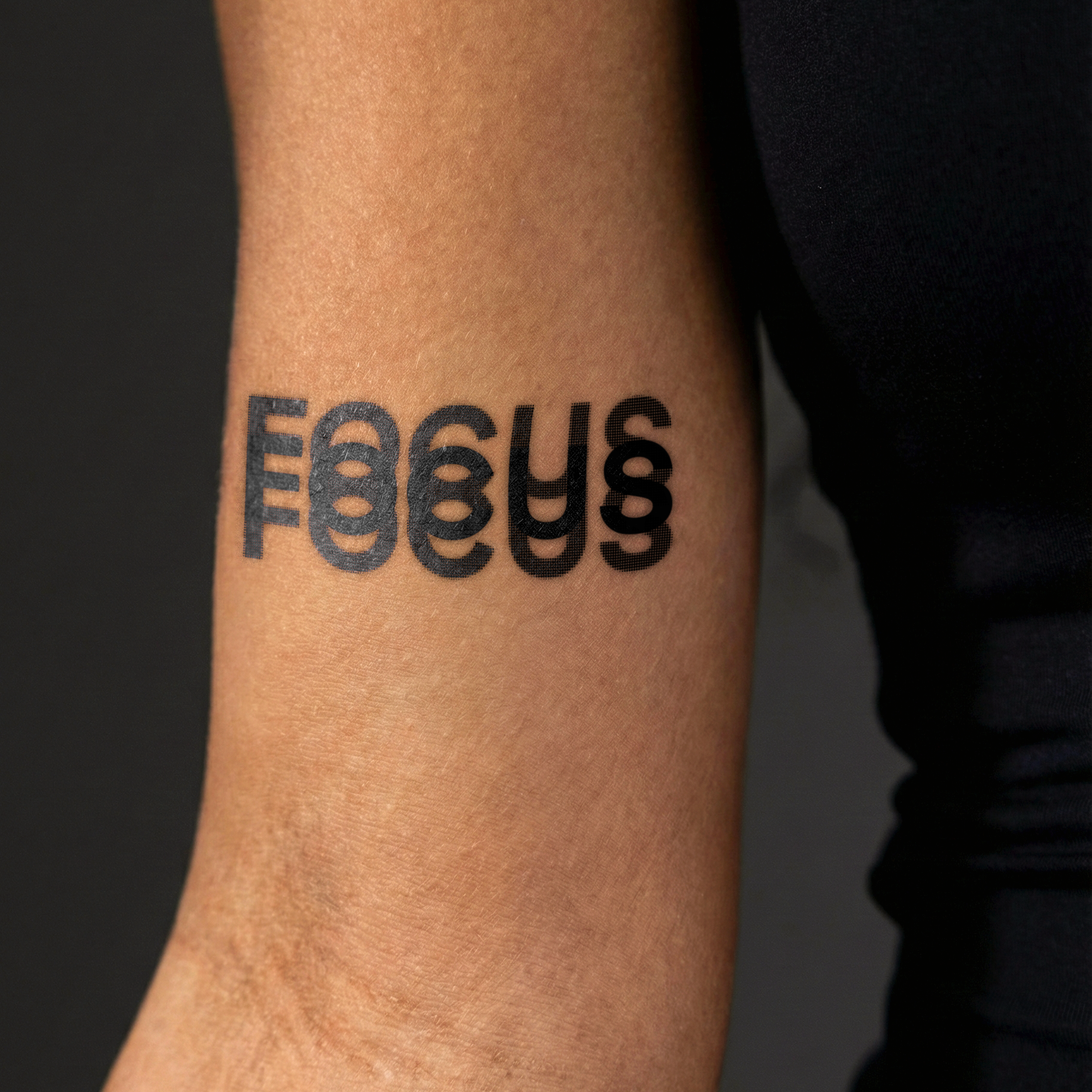 Tattoo of the word 'FOCUS' on a person's arm with a black background