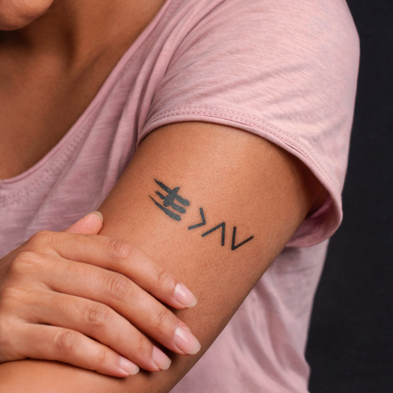 Person wearing a pink shirt with a tattoo on their arm
