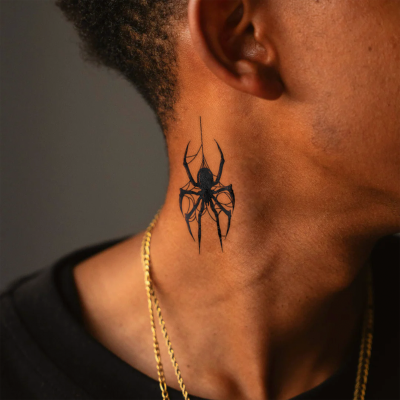 Black spider tattoo on a person's neck with a gold chain visible.