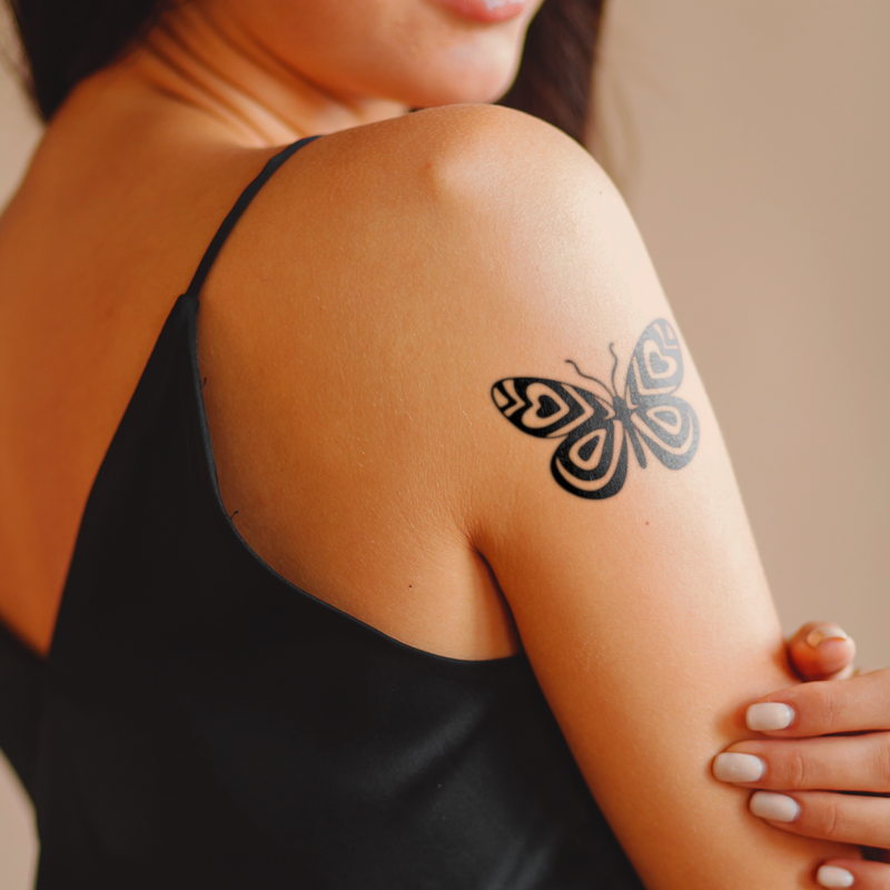 Person with a butterfly tattoo on their arm, wearing a black top.