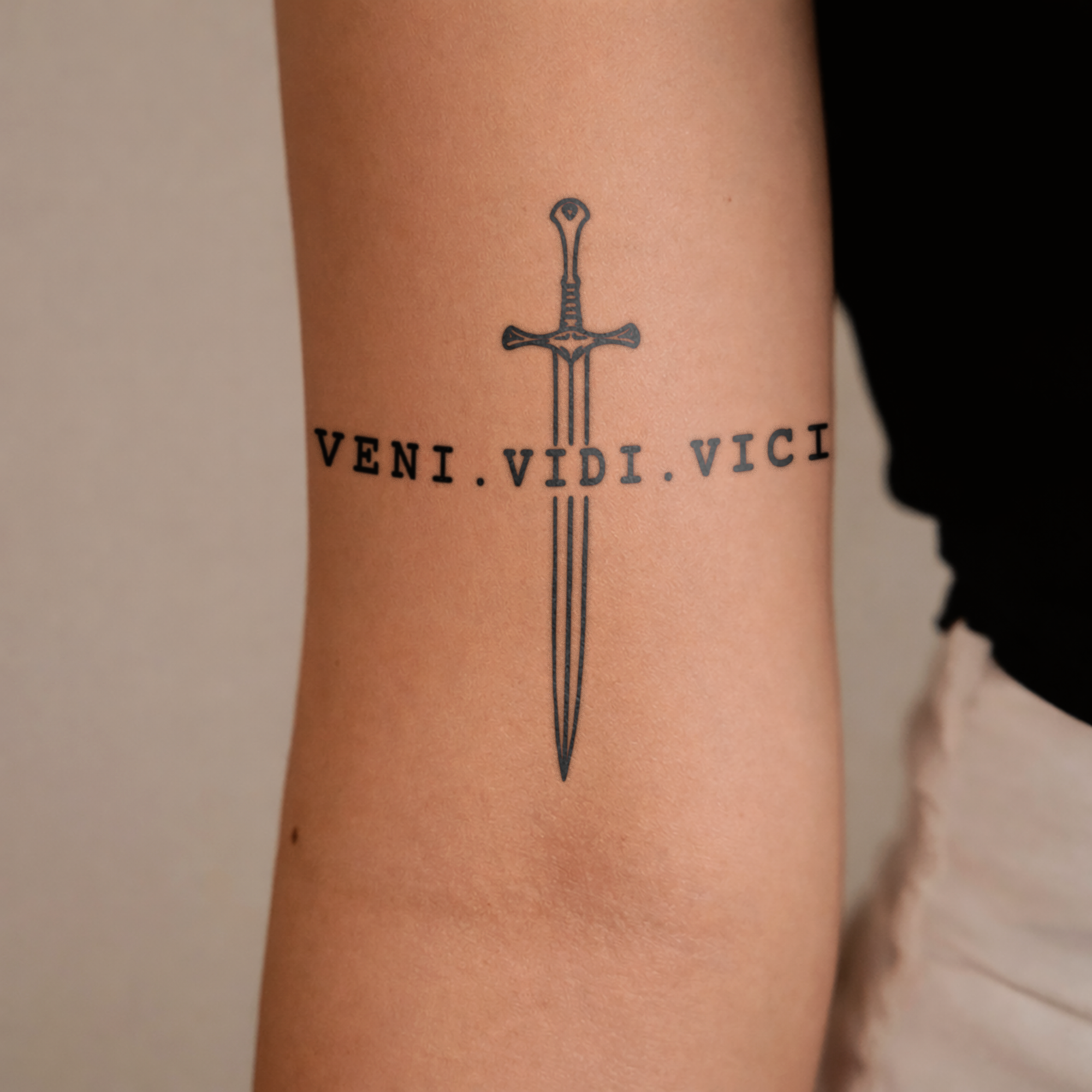 Tattoo of a sword and 'VENI.VIDI.VICI' on a person's arm.