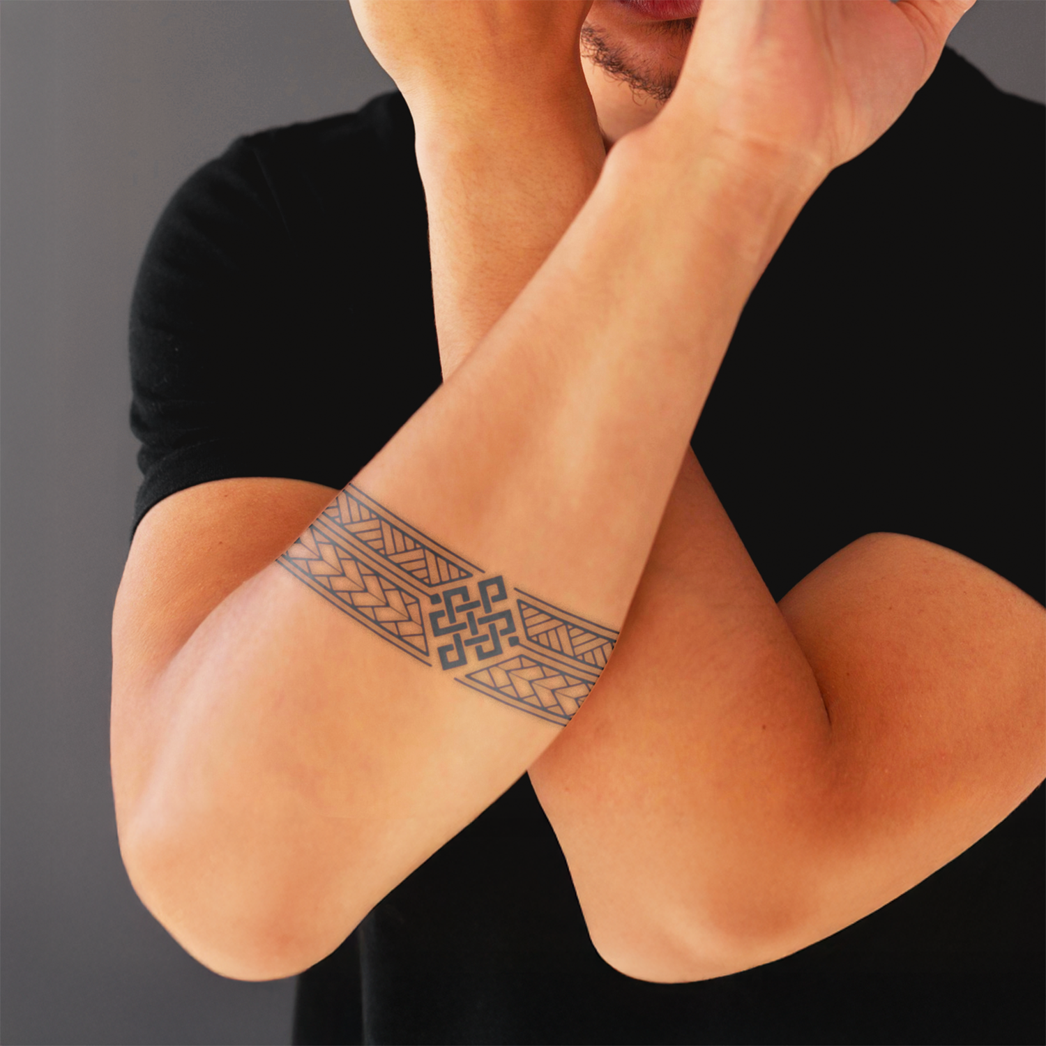 Person wearing a black shirt with a geometric tattoo on their arm against a gray background