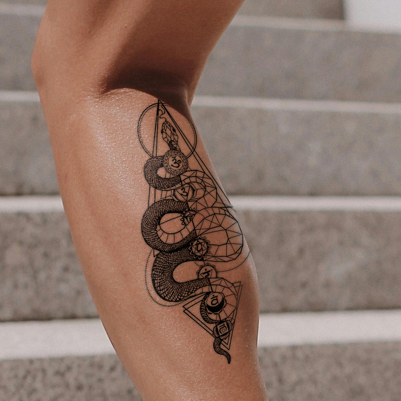 Tattoo of a snake and eye design on a person's leg with a staircase background
