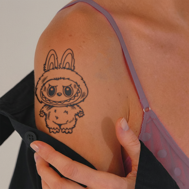 Tattoo of a cartoon character on a person's arm with a blurred background