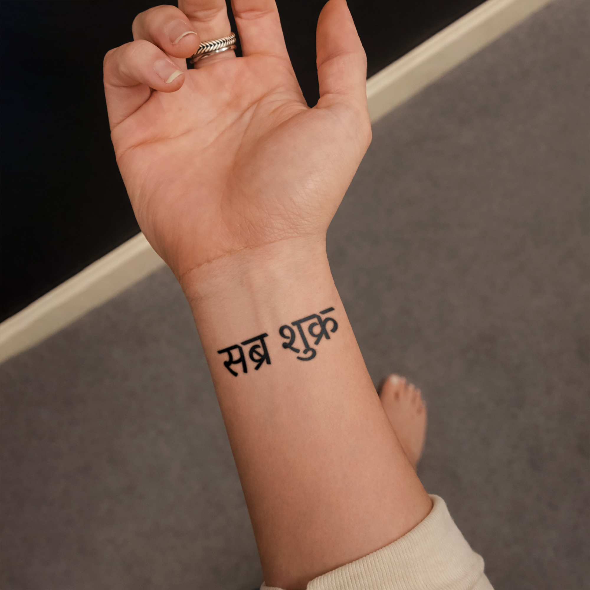 Hand with a black tattoo on wrist against a neutral background