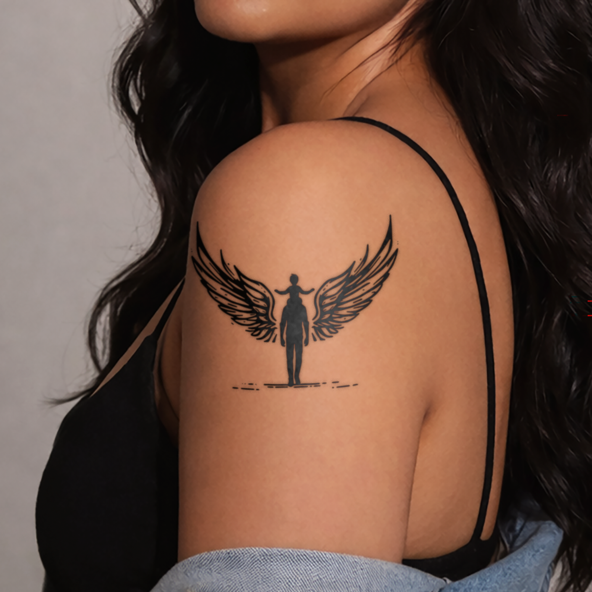 Person with a black tattoo of a figure with wings on their shoulder