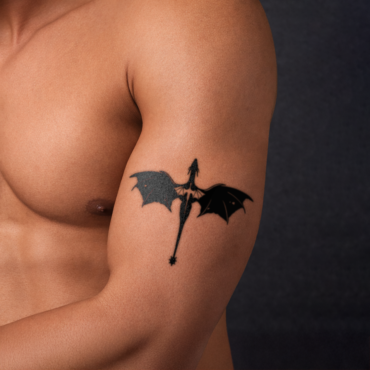 Tattoo of a black silhouette with wings on a person's arm against a dark background