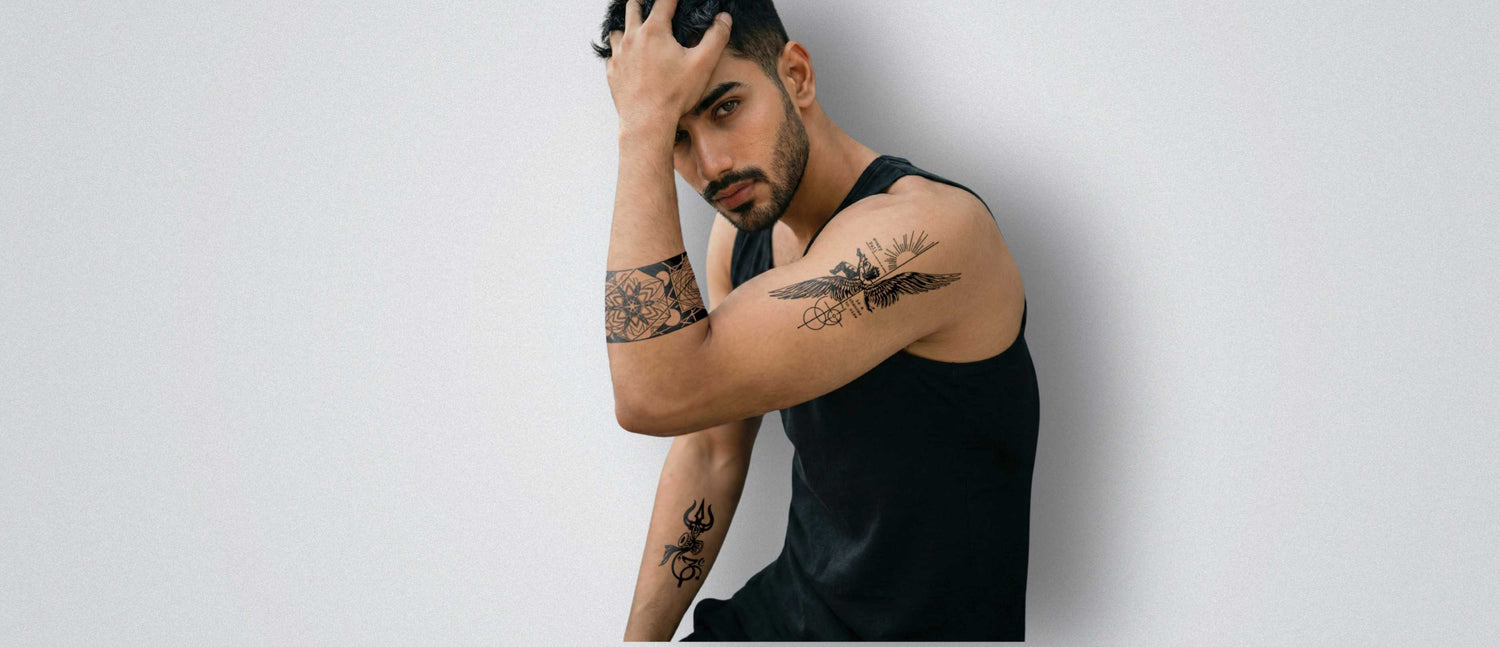 Man with tattoos on his arms against a plain background