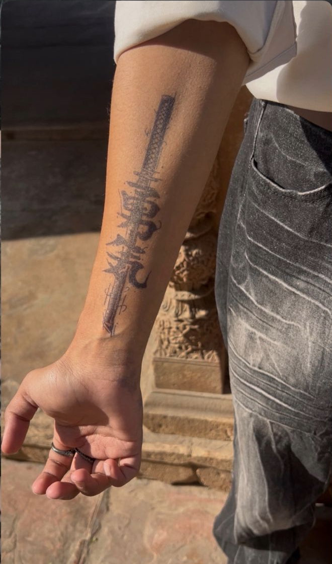 Person's arm with a tattoo in an outdoor setting